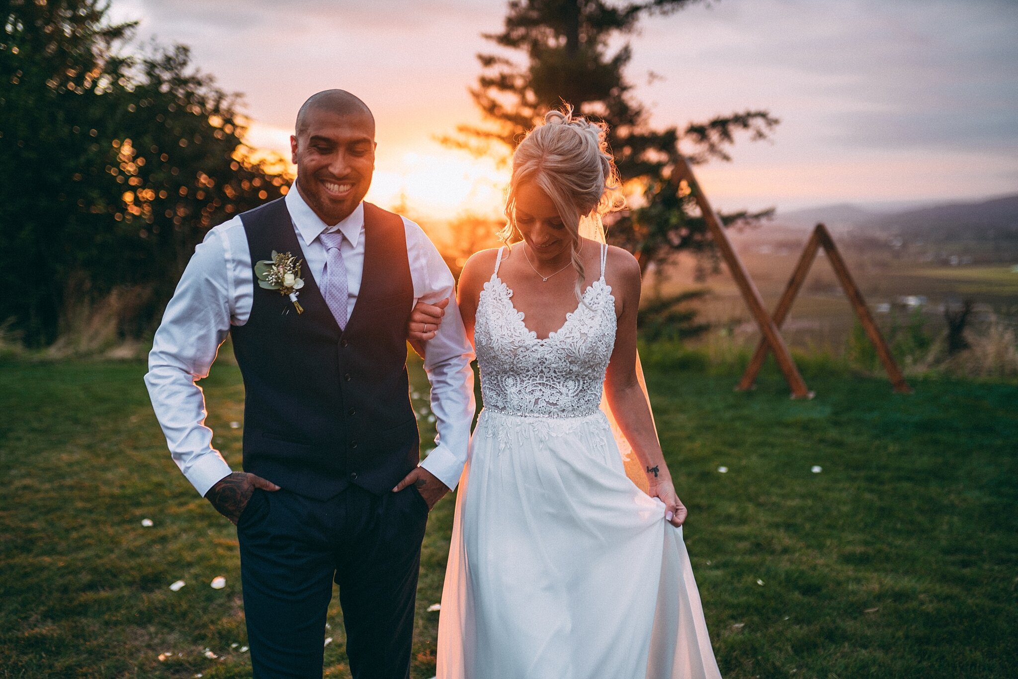 bride holding onto grooms arm for support at sunset smiling