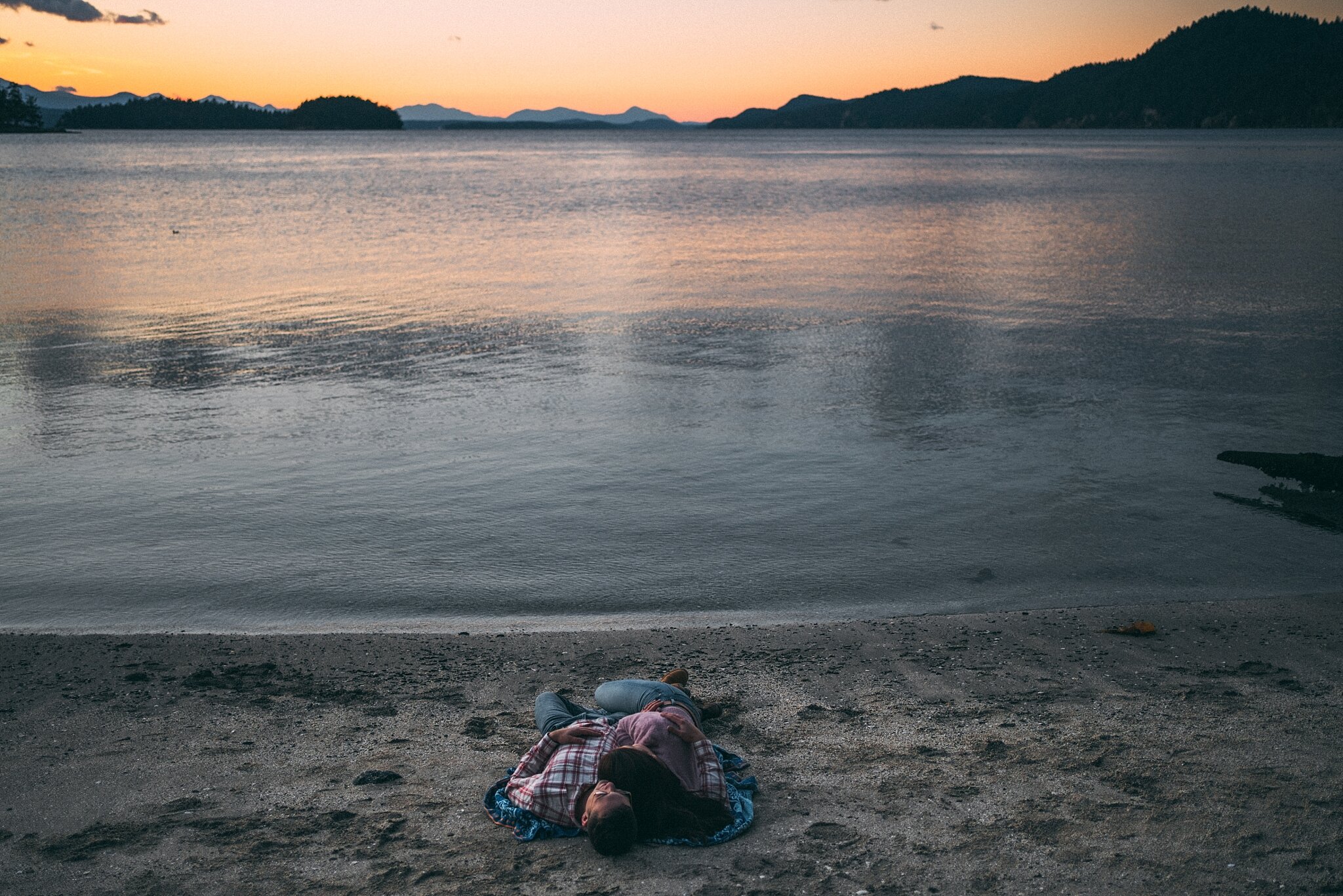 engaged couple cuddling beside ocean at galiano island