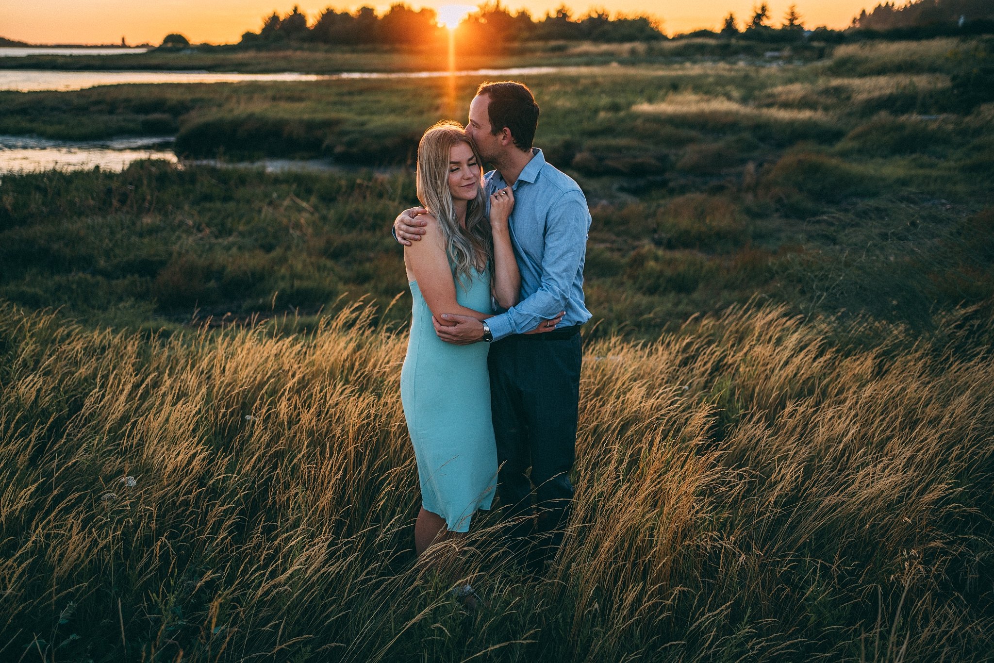 man kissing woman's forehead at sunset 