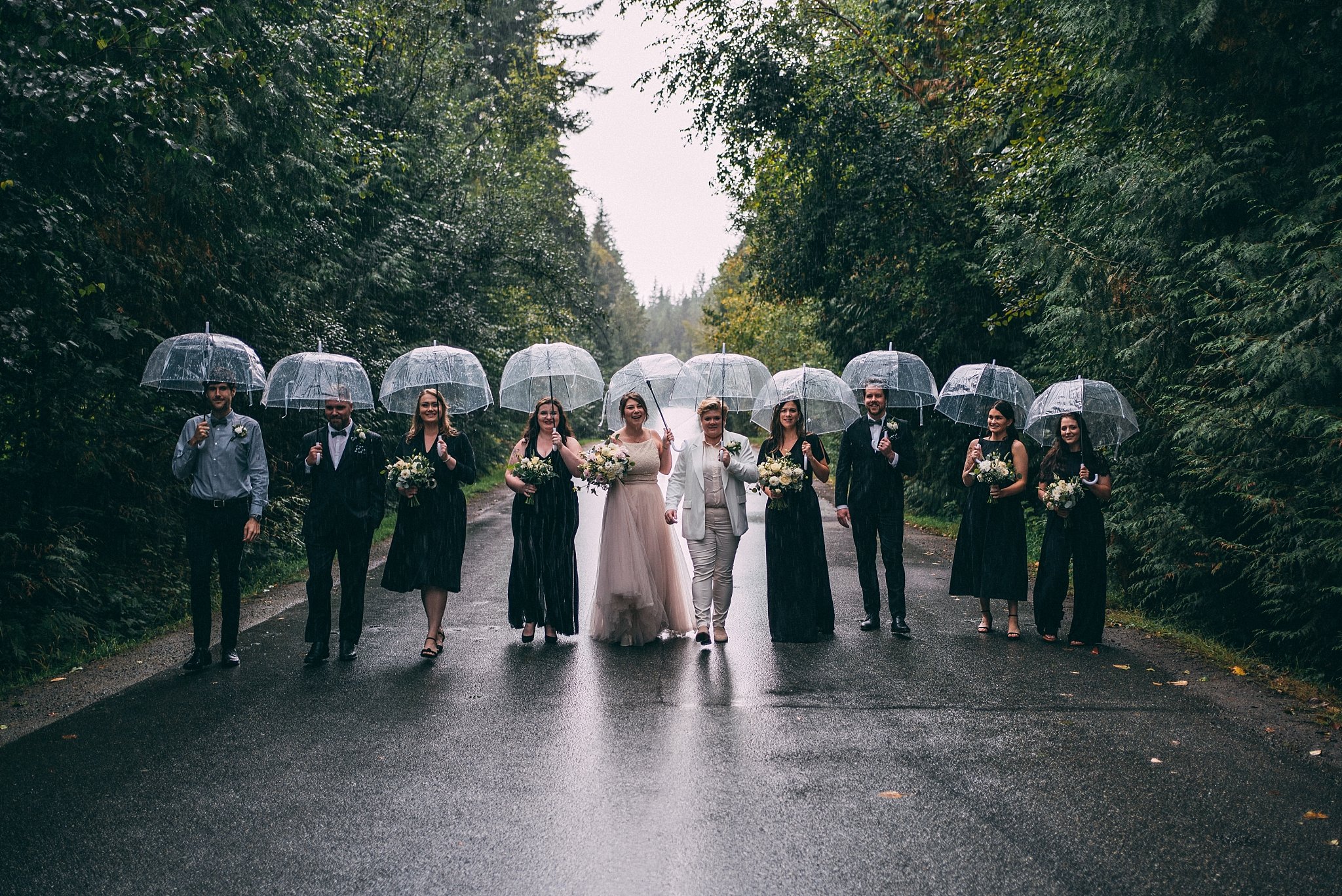wedding party holding umbrellas on road
