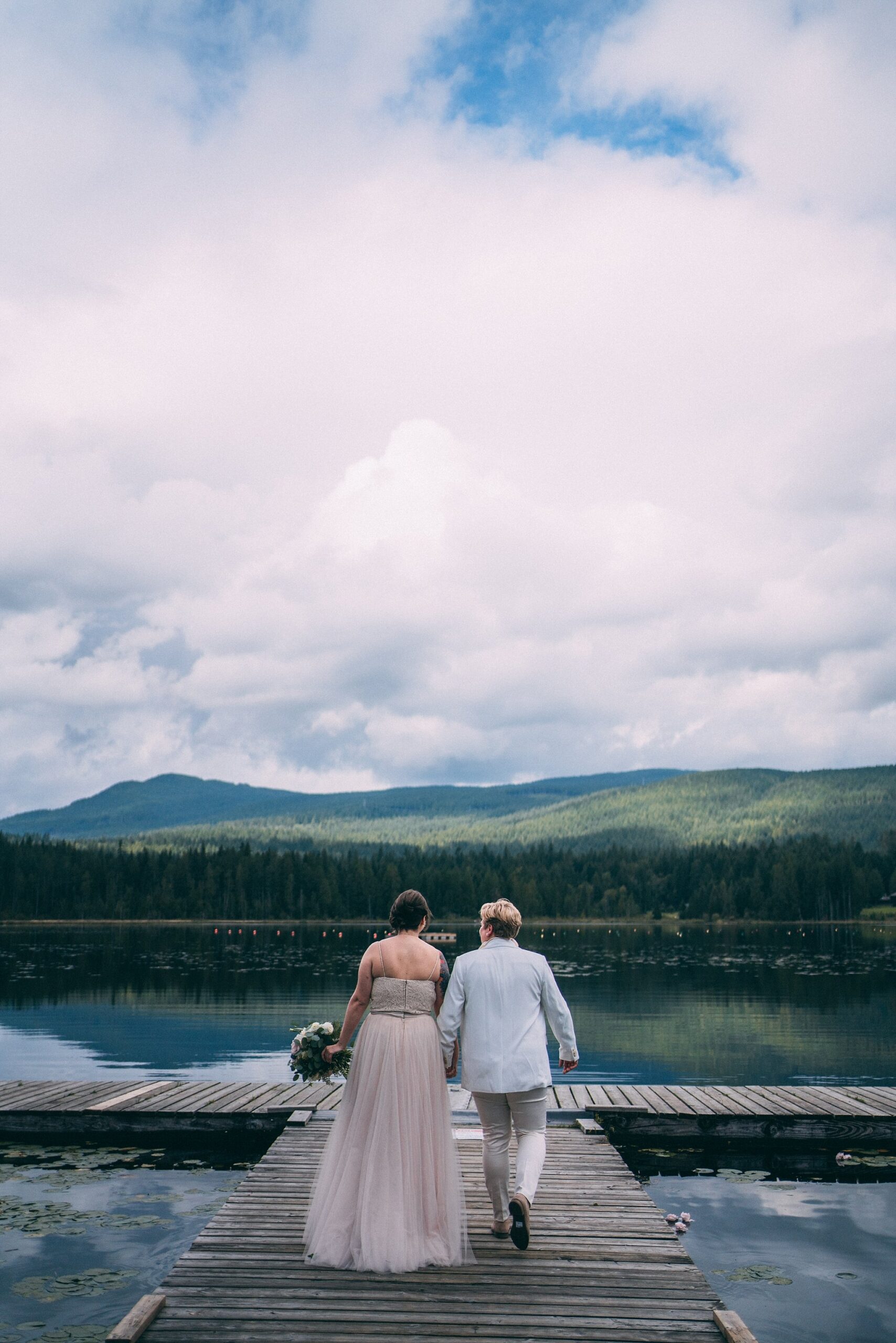 two brides walking on dock at whonnock lake on wedding day
