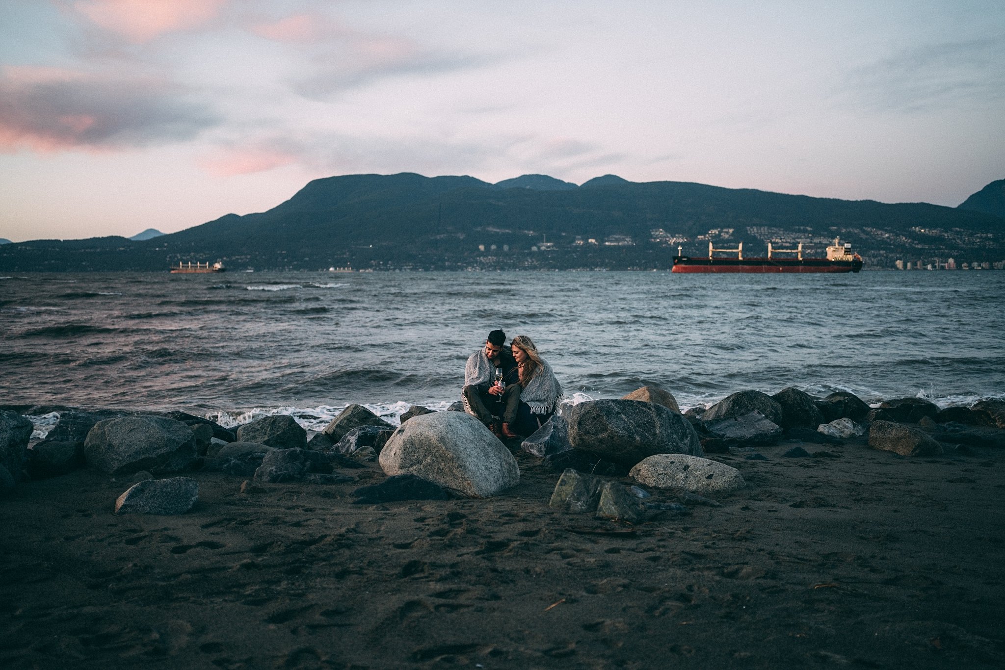 engaged couple sitting on beach in vancouver, b.c.