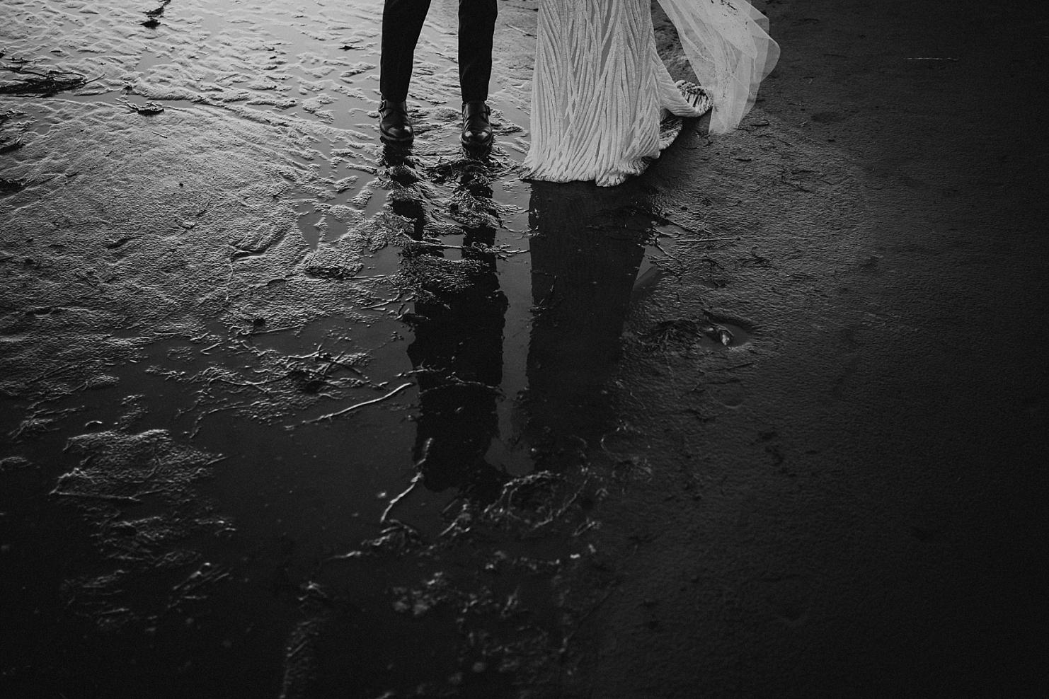 bride and groom in tidepool reflection on beach